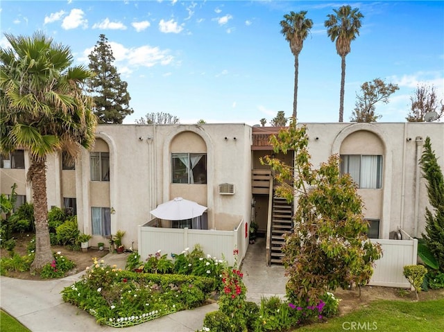 view of front of property with stucco siding, stairway, and fence