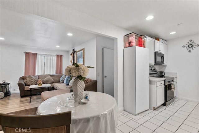 kitchen with freestanding refrigerator, black microwave, recessed lighting, stainless steel electric range, and white cabinets
