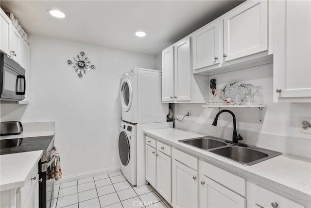 washroom with stacked washer and dryer, laundry area, a sink, recessed lighting, and light tile patterned floors