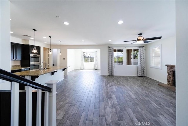 interior space with a sink, ceiling fan, a fireplace, recessed lighting, and dark wood-type flooring