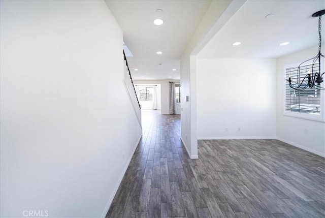 hall featuring recessed lighting, dark wood-type flooring, baseboards, and an inviting chandelier