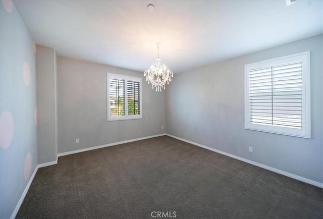 unfurnished room with a notable chandelier, baseboards, and dark colored carpet