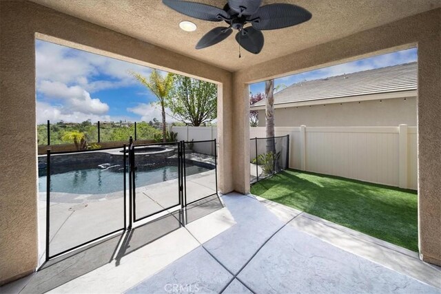view of patio / terrace featuring a fenced backyard, a pool with connected hot tub, and a ceiling fan