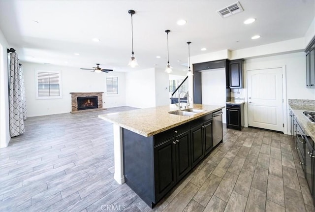 kitchen with visible vents, ceiling fan, light wood finished floors, dishwasher, and a sink