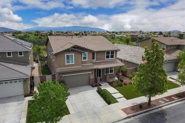 view of front of house with a mountain view, stucco siding, a tile roof, an attached garage, and driveway