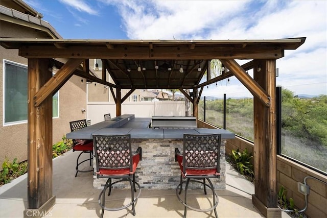 view of patio / terrace with area for grilling, outdoor wet bar, grilling area, fence, and a gazebo