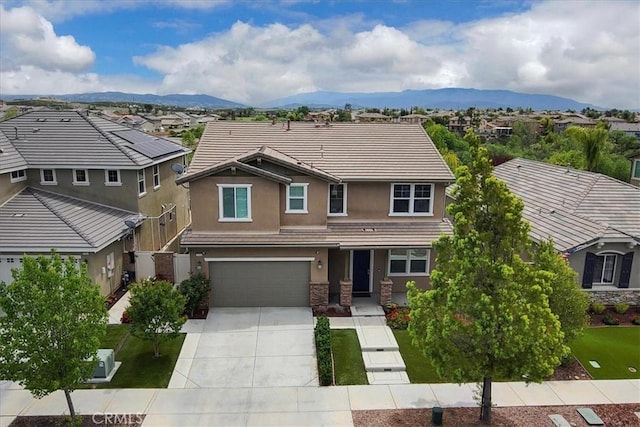 view of front of property featuring a garage, a residential view, driveway, and a tiled roof