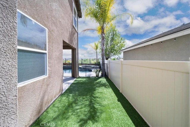 view of yard with a fenced backyard and a pool with connected hot tub