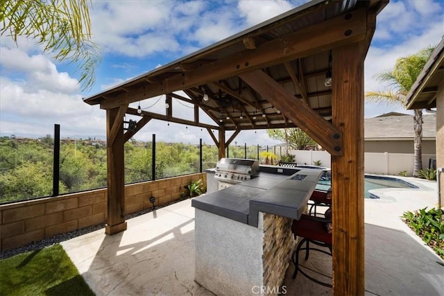 view of patio featuring a grill, a gazebo, exterior kitchen, outdoor wet bar, and a fenced backyard