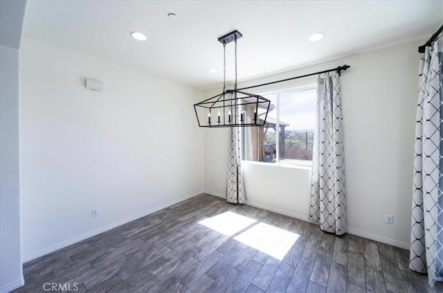 unfurnished dining area with recessed lighting, baseboards, an inviting chandelier, and wood finished floors