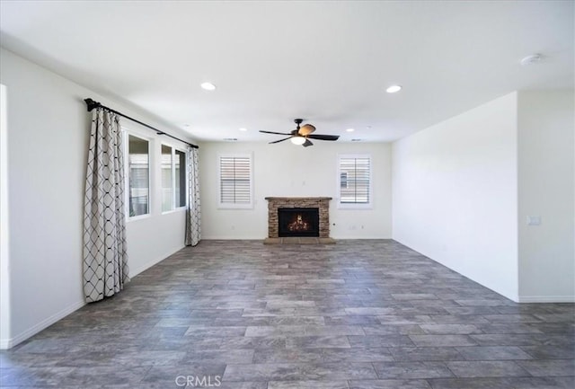 unfurnished living room with a ceiling fan, a warm lit fireplace, recessed lighting, wood finished floors, and baseboards