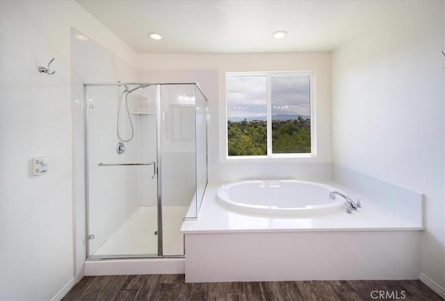 bathroom with a shower stall, a garden tub, and wood finished floors