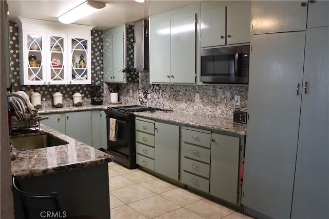 216 Barros St, Patterson, CA 95363 - kitchen with black range with gas stovetop, wall chimney exhaust hood, light tile patterned flooring, stainless steel microwave, and a sink