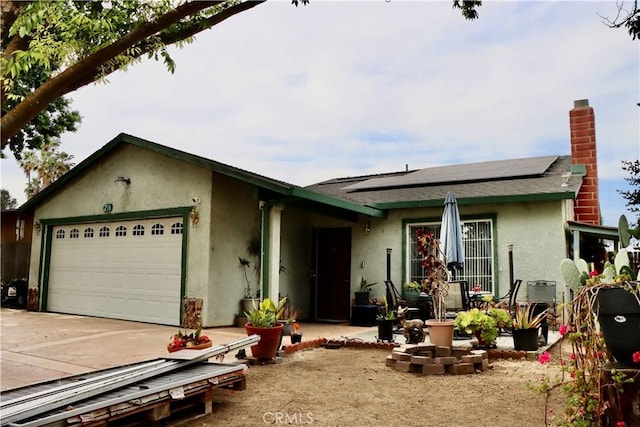 216 Barros St, Patterson, CA 95363 - ranch-style home with concrete driveway, stucco siding, a chimney, an attached garage, and roof mounted solar panels