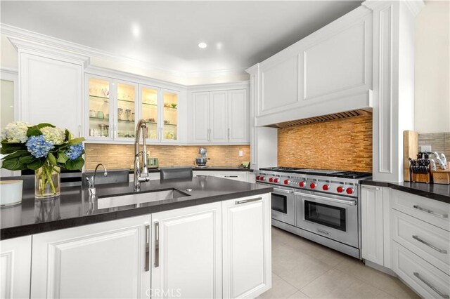 5366 Collingwood Cir, Calabasas, CA 91302 - kitchen with range with two ovens, a sink, dark countertops, white cabinetry, and crown molding