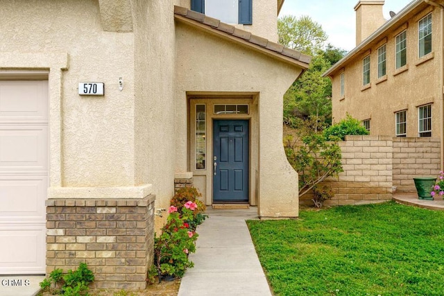 doorway to property with a garage, fence, and stucco siding