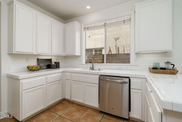 kitchen with a sink, tile counters, stainless steel dishwasher, and white cabinetry