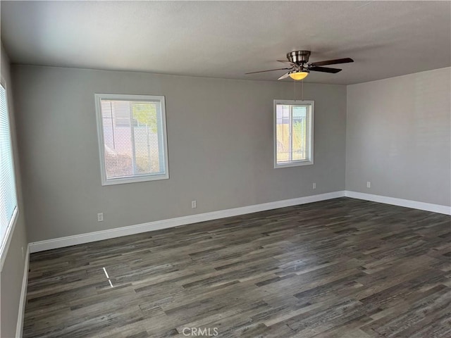 empty room featuring a ceiling fan, baseboards, and dark wood finished floors