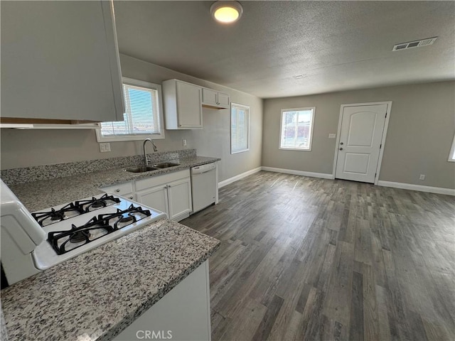 kitchen featuring dark wood-style floors, visible vents, a sink, white dishwasher, and light stone countertops