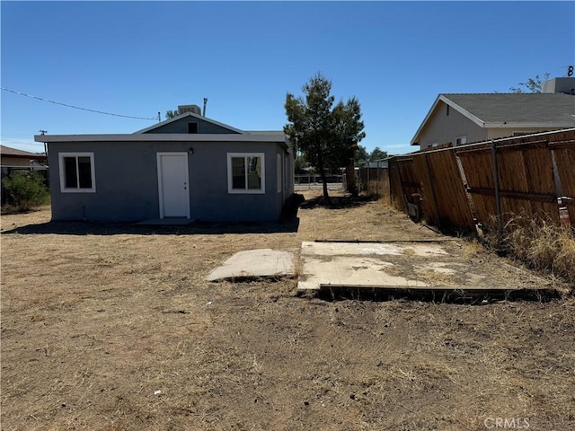 back of house featuring stucco siding, cooling unit, and fence