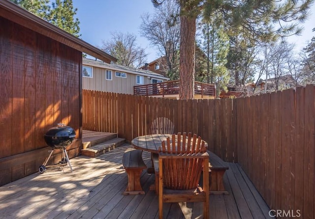 wooden terrace with grilling area, outdoor dining space, and fence