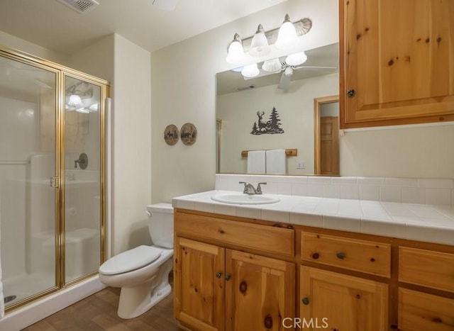 full bath featuring a shower stall, wood finished floors, toilet, and vanity