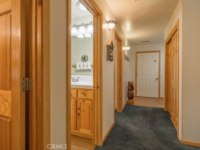 hallway with carpet, baseboards, and a sink