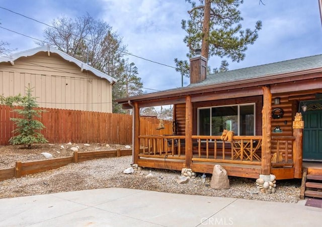 back of house featuring a chimney and fence