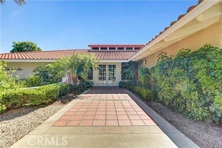 doorway to property with a tile roof, french doors, and stucco siding