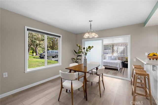 dining space with light wood-type flooring, baseboards, and a notable chandelier