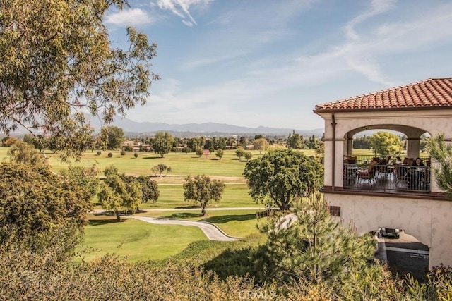 view of community featuring a lawn, view of golf course, and a mountain view