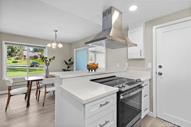 kitchen featuring stainless steel range with electric stovetop, island exhaust hood, light countertops, white cabinets, and a peninsula