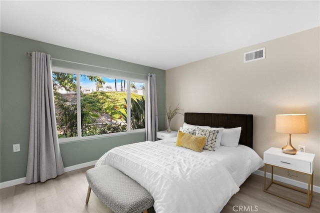 bedroom with wood finished floors, visible vents, and baseboards