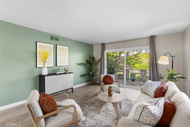 living room with wood finished floors, visible vents, and baseboards