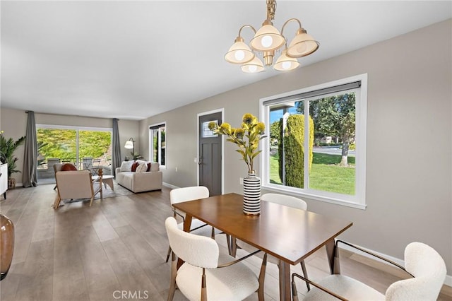 dining space with light wood finished floors, an inviting chandelier, baseboards, and a wealth of natural light