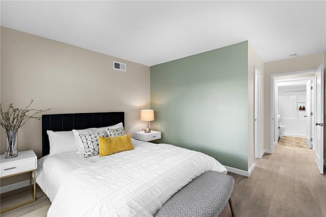 bedroom featuring light wood-type flooring, visible vents, and baseboards