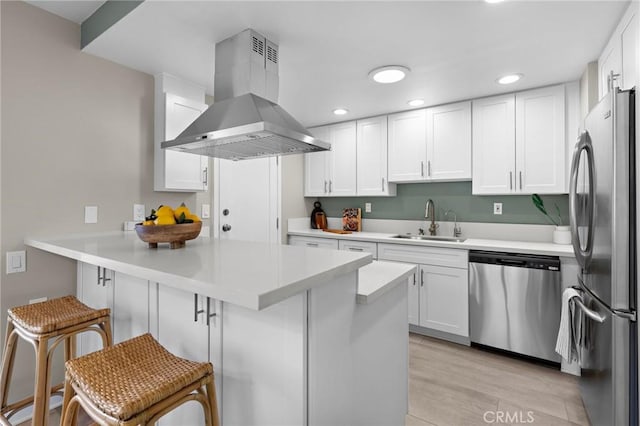 kitchen with a breakfast bar, island range hood, a sink, a peninsula, and appliances with stainless steel finishes