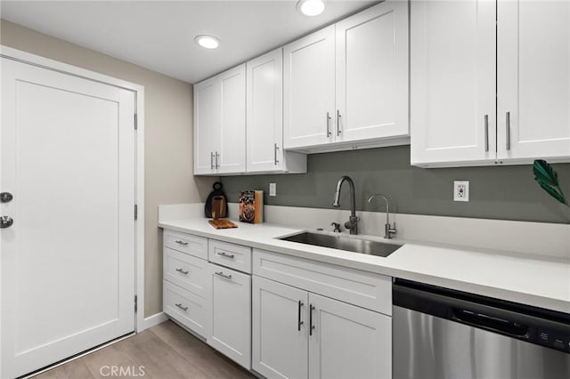 kitchen with white cabinets, recessed lighting, light countertops, stainless steel dishwasher, and a sink