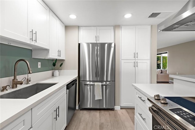 kitchen with visible vents, white cabinetry, stainless steel appliances, and a sink
