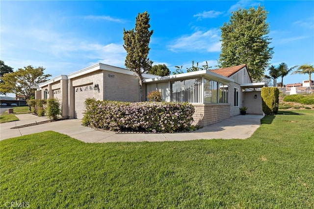 view of front of home featuring stucco siding, driveway, a front yard, and a garage