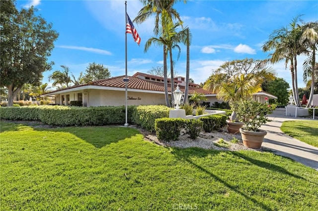 view of side of home featuring a lawn, a tiled roof, and stucco siding