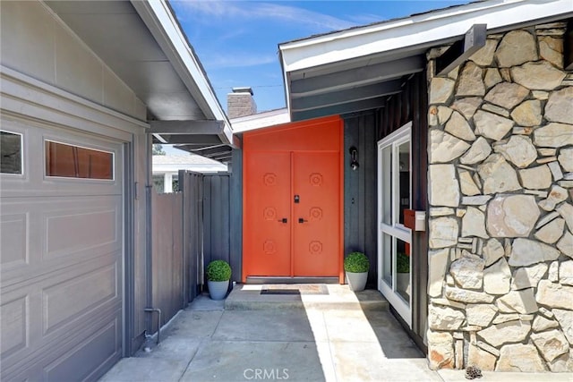 property entrance featuring stone siding and fence