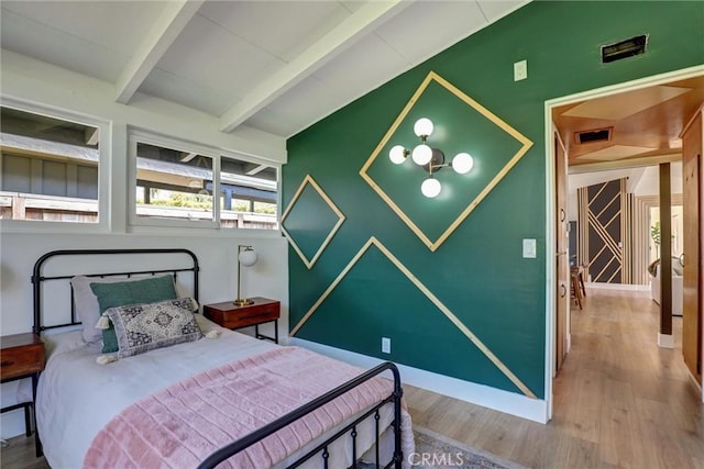 bedroom with baseboards, wood finished floors, and beamed ceiling