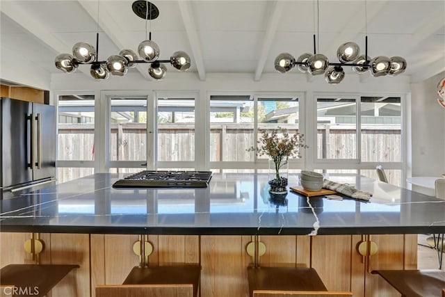 kitchen with beamed ceiling, dark countertops, a kitchen bar, and stainless steel appliances