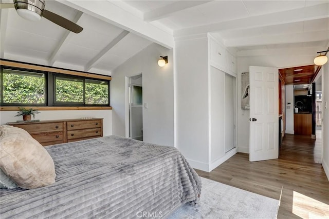 bedroom featuring baseboards, vaulted ceiling with beams, and wood finished floors