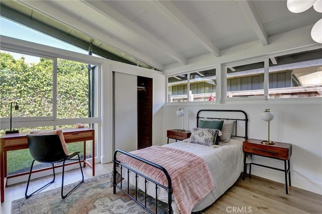 bedroom featuring wood finished floors and vaulted ceiling with beams