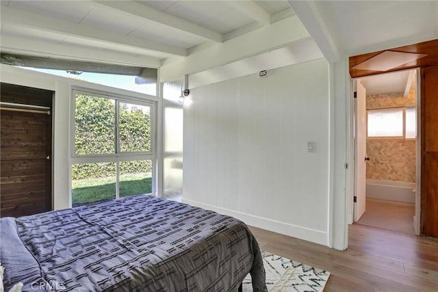 bedroom with lofted ceiling with beams, baseboards, and wood finished floors