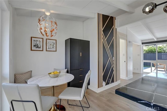 dining area with baseboards, vaulted ceiling with beams, and light wood finished floors