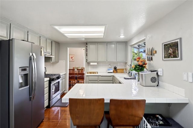 312 Barrington Cir, Redlands, CA 92374 - kitchen featuring stainless steel appliances, tile countertops, a peninsula, and gray cabinetry
