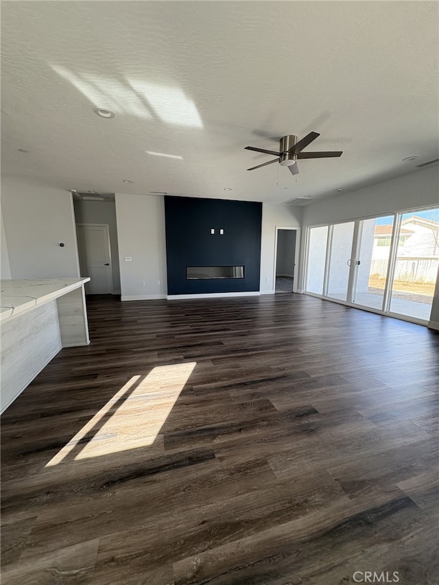 12525 Spring Valley Pkwy, Victorville, CA 92395 - unfurnished living room featuring dark wood-type flooring, a ceiling fan, and baseboards
